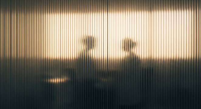 Silhouette of people behind frosted glass represent HIPAA privacy and confidential medical consulting in a professional office setting