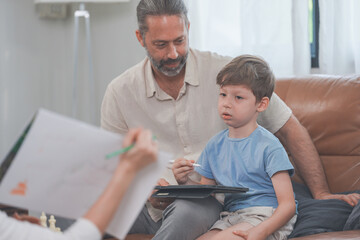 Fototapeta premium A loving mother, father and son use a touchscreen tablet together at home in a bright modern living room, celebrating home life and family connection, as a family.