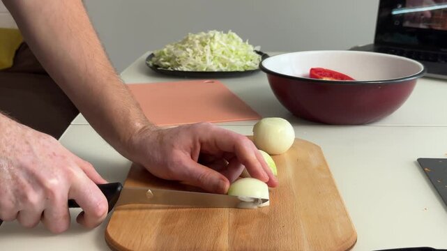 Hands slicing peeled onion into thin rings on wooden cutting board during home kitchen prep with knife, fresh texture, and tidy food preparation scene, with onion, slicing, knife, hand detail
