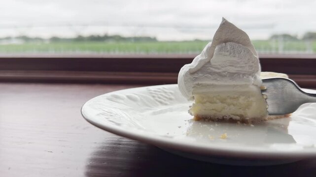 Half eaten cheesecake with fork slowly coming back for more