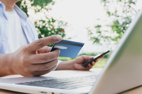 Business professional holding credit card for secure online payment using smartphone and laptop, digital banking transaction, e commerce shopping, cashless payment and financial technology concept