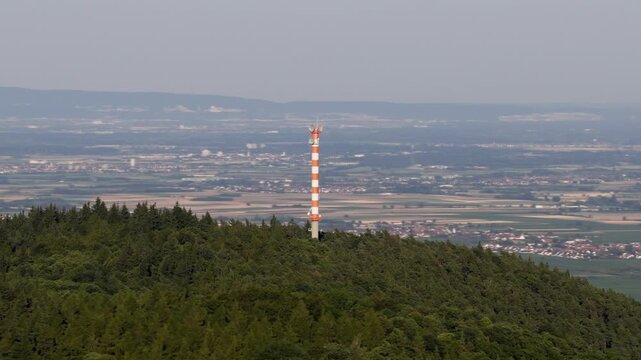 Modern Cell Tower Standing Tall on a Forested Hill Overlooking a Vast Rural Landscape