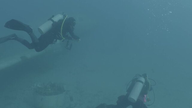 log footage of an airplane wreck underwater scuba divers to explore  metal on ocean floor