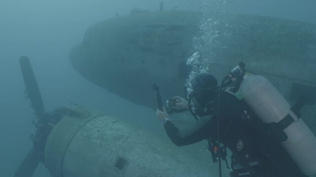 log footage of an airplane wreck underwater scuba divers to explore  metal on ocean floor