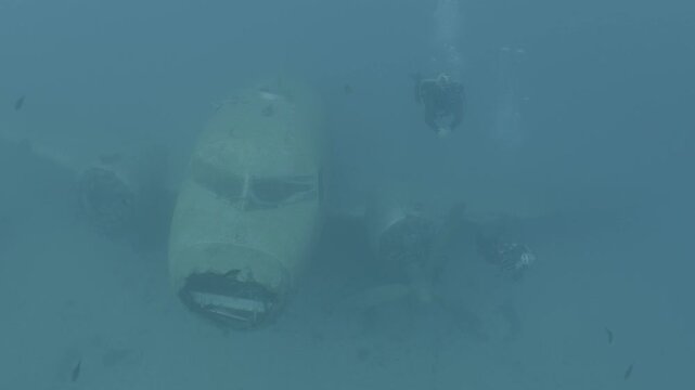 log footage of an airplane wreck underwater scuba divers to explore  metal on ocean floor
