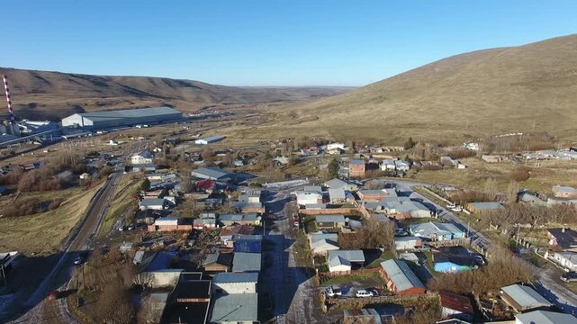 4K aerial drone footage flying over Julia Dufour, a Patagonian megausina in Santa Cruz, Argentina. Scenic urban landscape surrounded by rugged mountains, showcasing the beauty of southern Patagonia.