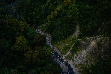 Thin thread-like waterfall cascading down a dark forested mountain cliff into a hidden valley in the Kokonoe highlands of Kyushu. © EdwardRT