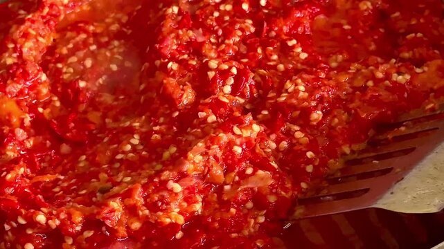 Close up of stirring traditional fried red sambal chili paste