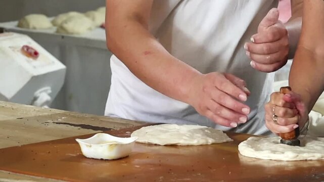 Traditional bread stamp with metal pins creates the decorative center pattern of authentic Uzbek flatbread before baking. Artisan bakery showing handcrafted bread making using traditional techniques.