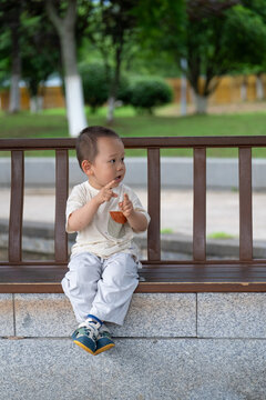 Young child waving while standing on wooden bench