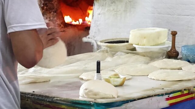 Traditional bread stamp with metal pins creates the decorative center pattern of authentic Uzbek flatbread before baking. Artisan bakery showing handcrafted bread making using traditional techniques.