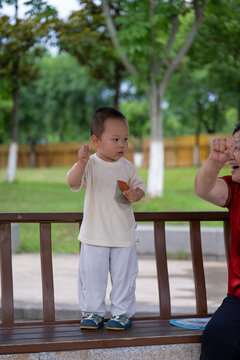 Asian toddler pointing upward against green background