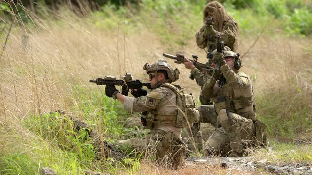 Special operations team gathers during a military training scenario with smoke effects, demonstrating coordination and mission preparation