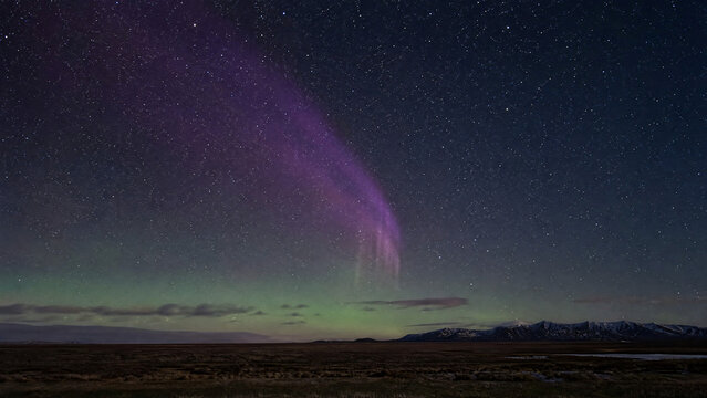 STEVE aurora phenomenon as purple light ribbon over arctic tundra with green airglow