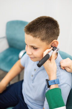 Vertical photo of a child between 10 and 12 years old during an ear examination with an otoscope in an ENT clinic. Concept of ear infection prevention in children