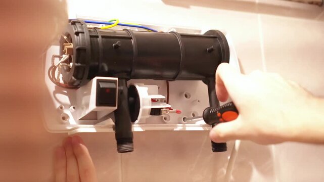  A technician expertly uses a screwdriver to perform maintenance on a water heater. The image captures the focus and precision required for efficient home appliance repair
