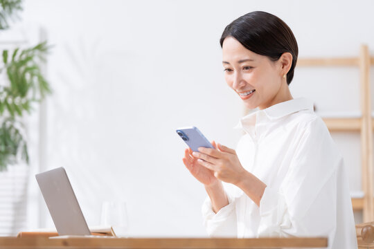 スマホを持ってパソコンを使う女性
