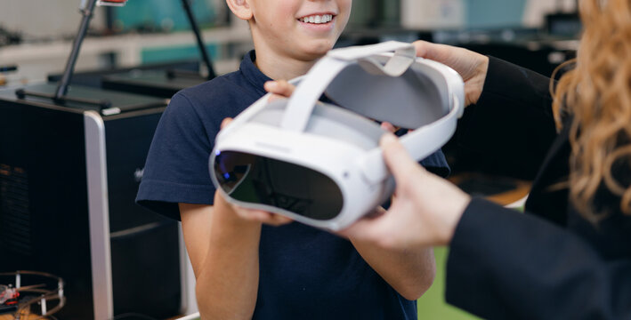 Boy receiving vr headset from instructor in tech workshop, technology science concept