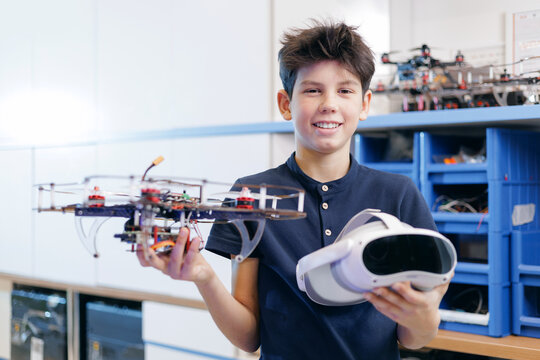 Portrait happy boy hold presenting robot drone and virtual reality headset in lab, STEM education future technology banner