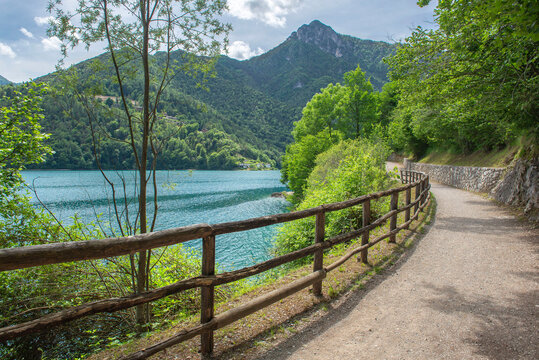 Bicycle road and foot path over a lake surrounded by mountains and borded lush edge  in trento country, Italy