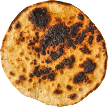 burnt roti flatbread isolated white background, charred black spots on round cooked wheat dough, top view in close-up