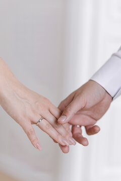 Close-up of newlywed couple holding hands showing wedding rings