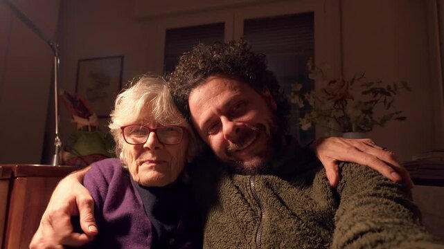 Adult son and elderly mother laughing during a video call celebrating family bonding and unconditional suport