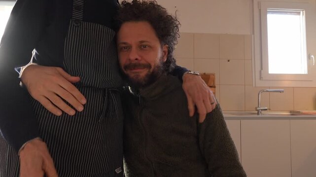 Affectionate mother hugging her adult son in the kitchen expressing unconditional family love and parental support