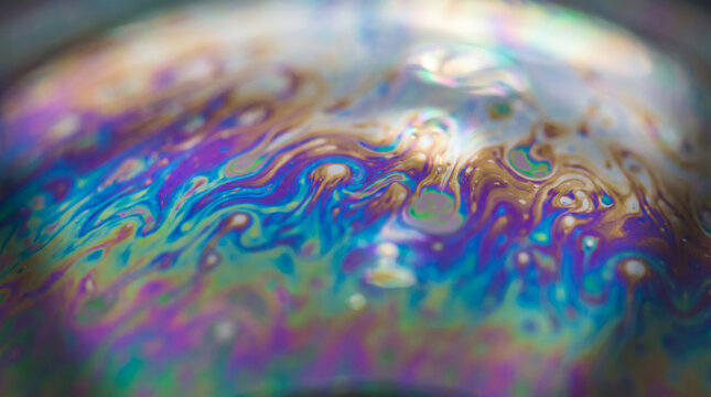 Close-up of iridescent bubble texture with vibrant colors. Abstract soap film with swirling rainbow hues