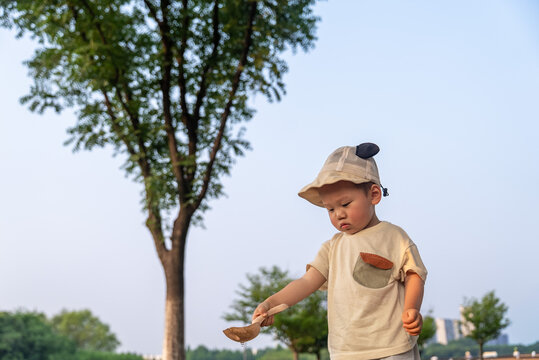 Young Asian child watering plants in park with cup