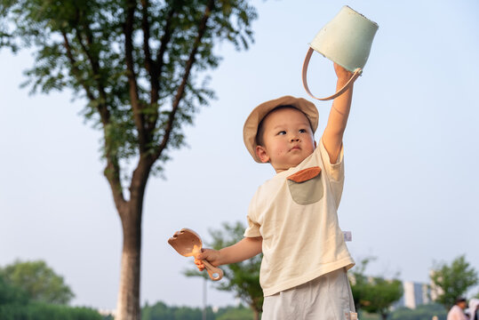 Happy Asian toddler watering garden with plastic cup