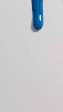 Vertical blue paint dripping down white textured paper background