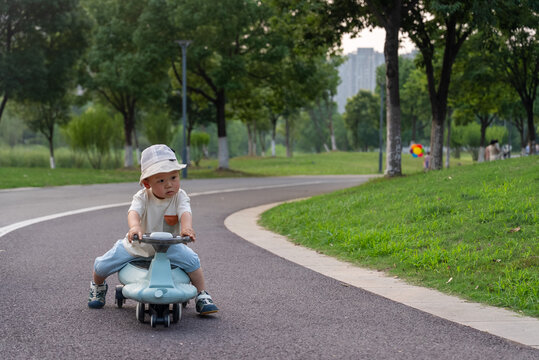Happy Asian toddler riding sit on toy car in park