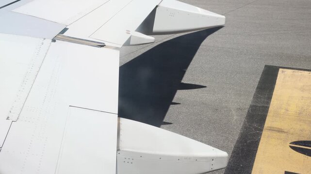 Airplane wing flaps extending on an airport runway during commercial air travel and tourism