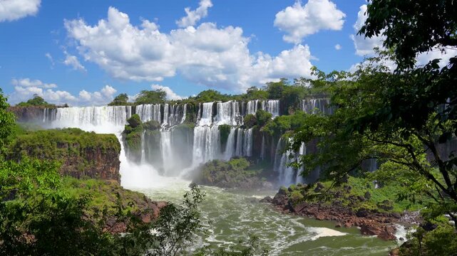 Dynamic capture of water in motion cascading over the rocky cliffs of Iguazu Falls; a vast, natural spectacle in South America with verdant jungle foliage framing the scene