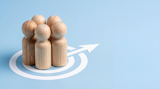 Group of wooden mannequin figures standing together on white target arrow symbol against blue background representing team building collaboration unity leadership success goal