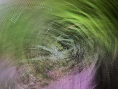 Abstract green and purple nature background with intentional camera movement and circular motion blur effect