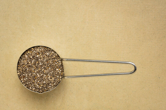 chia seeds in metal measuring scoop, top view against art paper, superfood concept