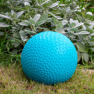heavy rubber slam ball filled with sand in a backyard, exercise and fitness concept