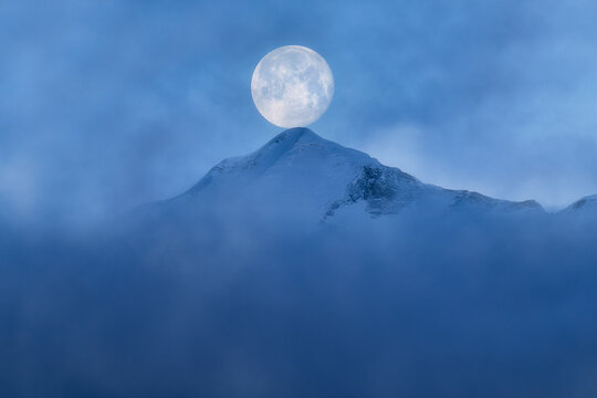 Full moon balanced on misty Tannhorn summit, Switzerland