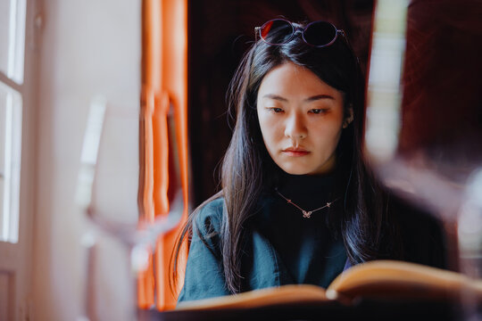 Young Woman Reading Menu by Window in Restaurant