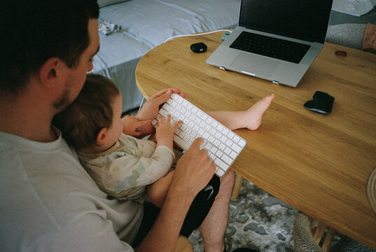 Anonymous father and baby typing on a keyboard