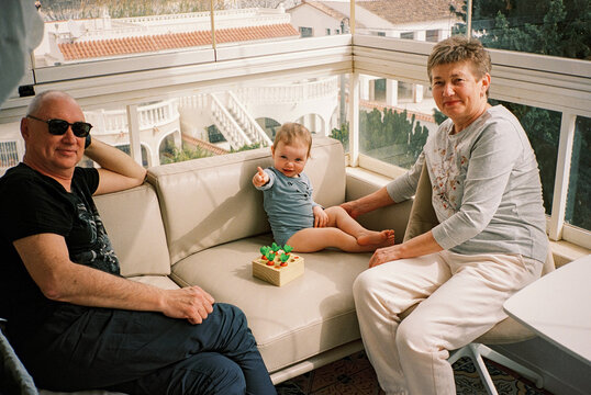 Grandparents with granddaughter ion a sunny terrace