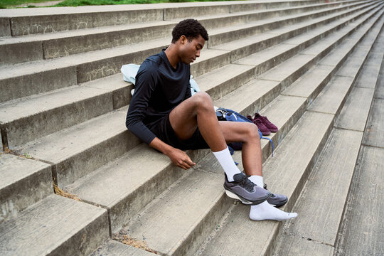 Young Man Ties Shoelaces on Steps in Urban Setting After Workout