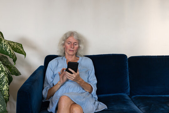 senior woman using smartphone at home, reading email