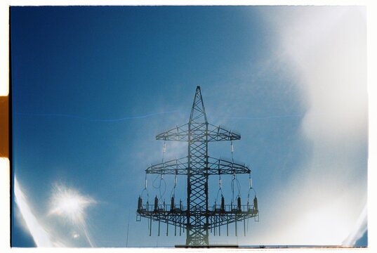 High voltage power tower stands against a clear blue sky