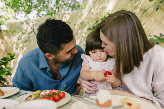 Father and mother with a toddler having breakfast outdoors