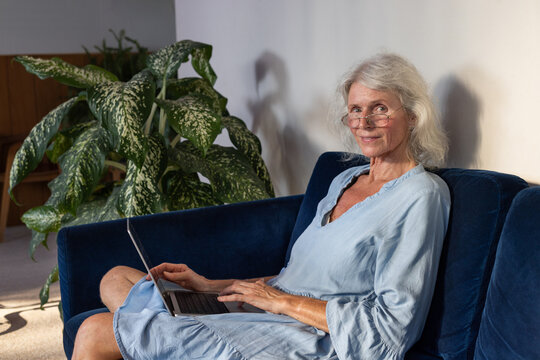 smiling senior woman entrepreneur with laptop computer on sofa at home