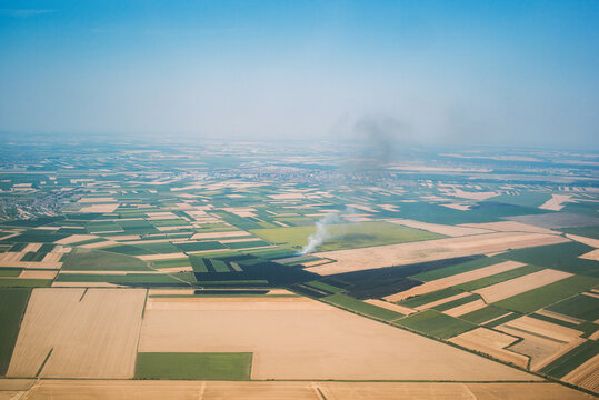 Smoke Rises From Fields in a Rural Area During Daylight Hours