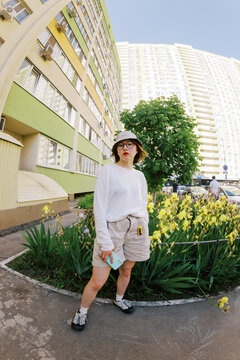 Woman Standing Near Flowers by a Tall Building in the City